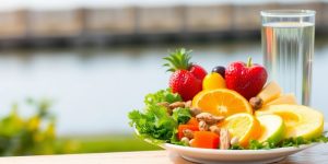 Fresh fruits and vegetables on a colorful plate outdoors.